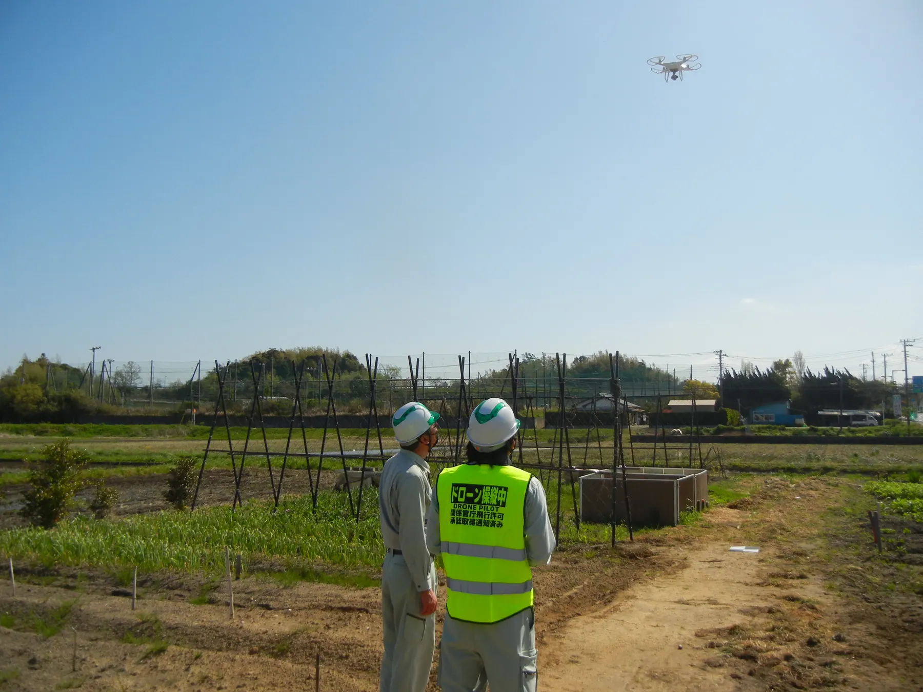 ドローン測量の現場で空を確認するスタッフ